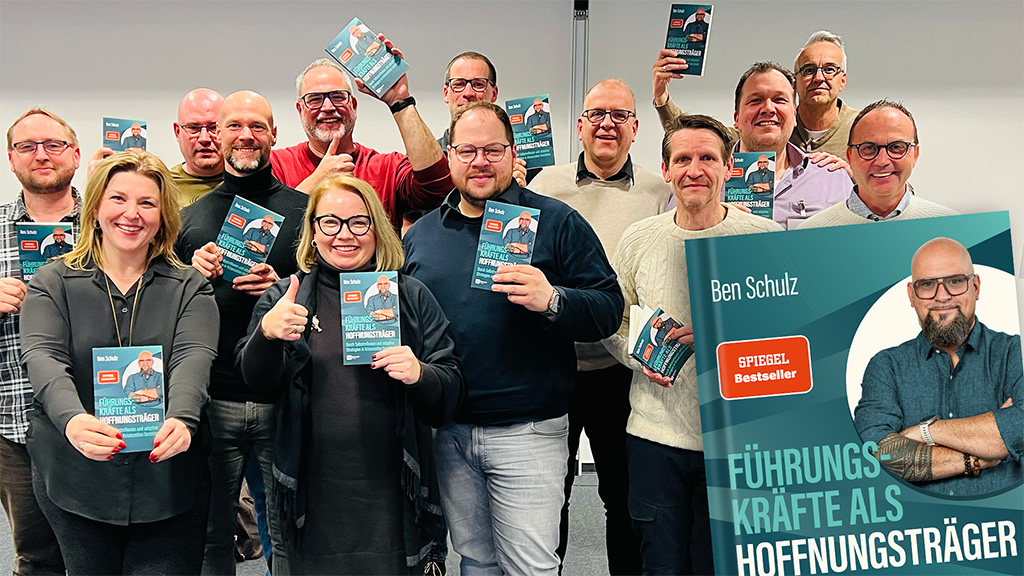 Eine Gruppe von Führungskräften hält das Buch "Führungskräfte als Hoffnungsträger" in den Händen